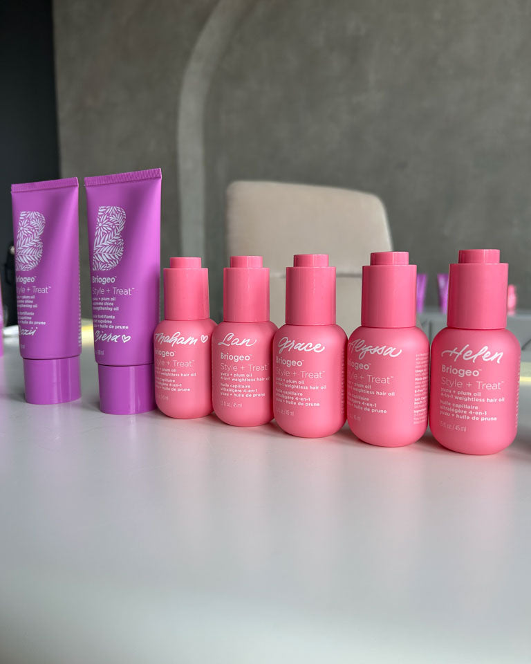 Row of pink Briogeo hair product bottles hand-lettered with guests’ names in white ink during a live brand activation by Toronto calligrapher JW Lettering.