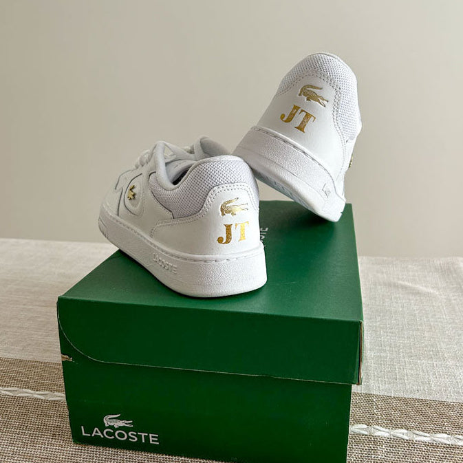 Pair of white sneakers personalized with gold foil initials using JW Lettering’s heat foiling service in Toronto.