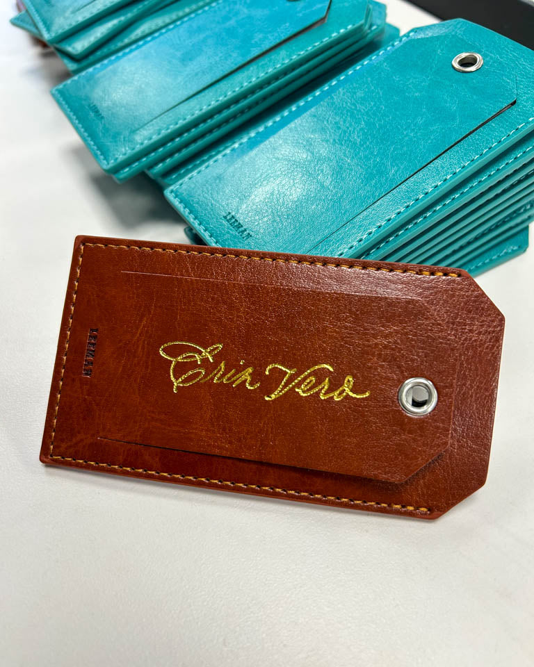 Close-up of gold foil calligraphy on a brown leather luggage tag personalized by JW Lettering in Toronto using a heat foiling pen.