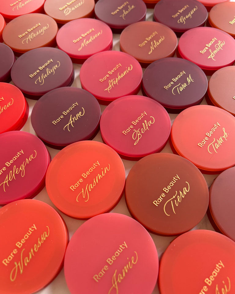 Rows of Rare Beauty compacts personalized with gold calligraphy names during a Toronto live event activation by JW Lettering calligrapher Jessie Wang.