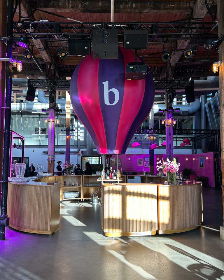 Beazley corporate event setup in Toronto with pink and purple hot-air-balloon decor and bar area.