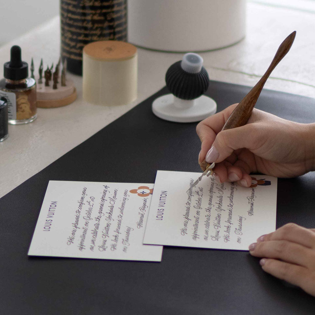 Toronto calligrapher Jessie Wang writing custom calligraphy on Louis Vuitton invitations during a live brand activation event.